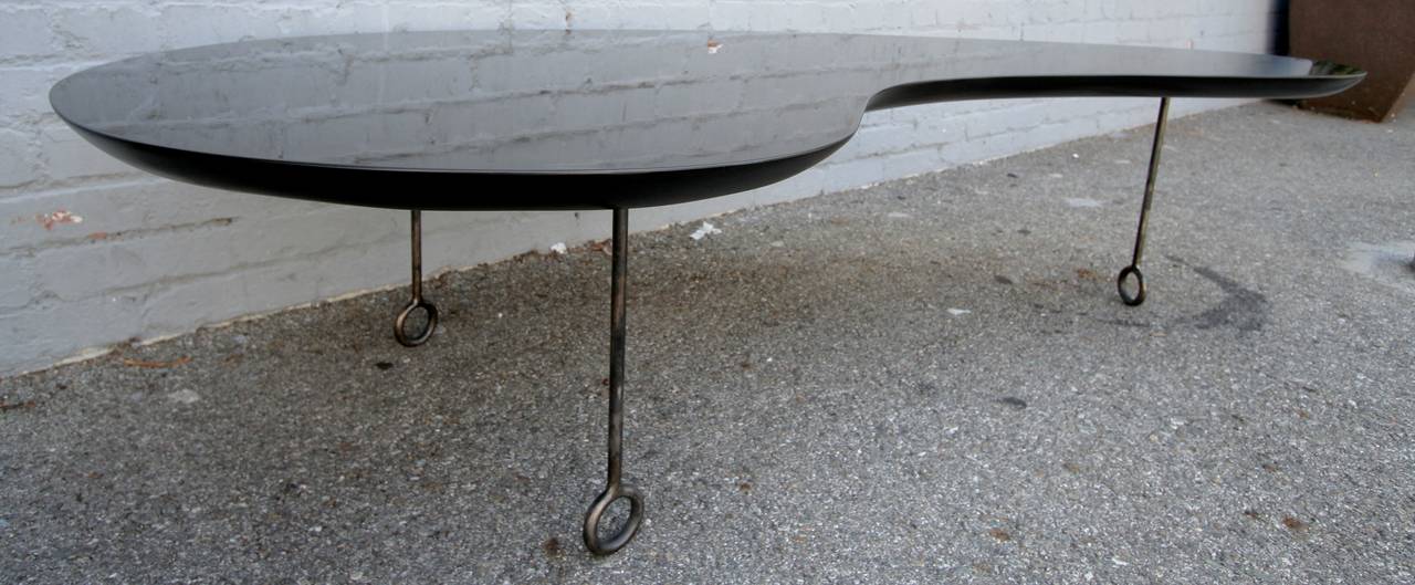 Royère-style coffee table with black lacquered wood top with metal legs.