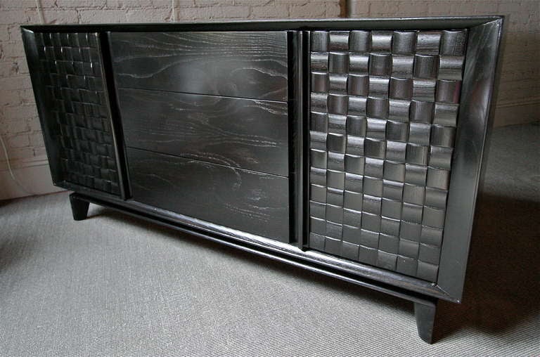 Basket weave sideboard made of ebonized oak by Paul Laszlo for Brown Saltman from the 1950s.  The two cabinets on either end each have an adjustable shelf.  Three drawers are located in the center.  The top drawer has built in dividers for flatware