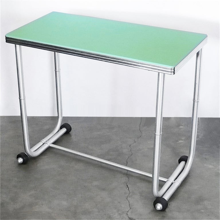 This wonderful table by Warren McArthur retains it's original jade green Vitrolite architectural glass top and rubber accents. This table has it's original anodized aluminum finish.