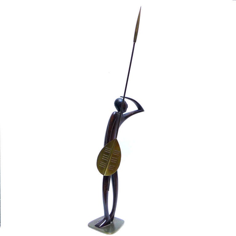 This wonderful sculpture was made by Hagenauer for the Wiener Werkstatte in the 1930's. The figure is carved warm walnut with a bronze base, loincloth, shield and spear. There is great detailing in the bronze and wonderful stylized movement in the