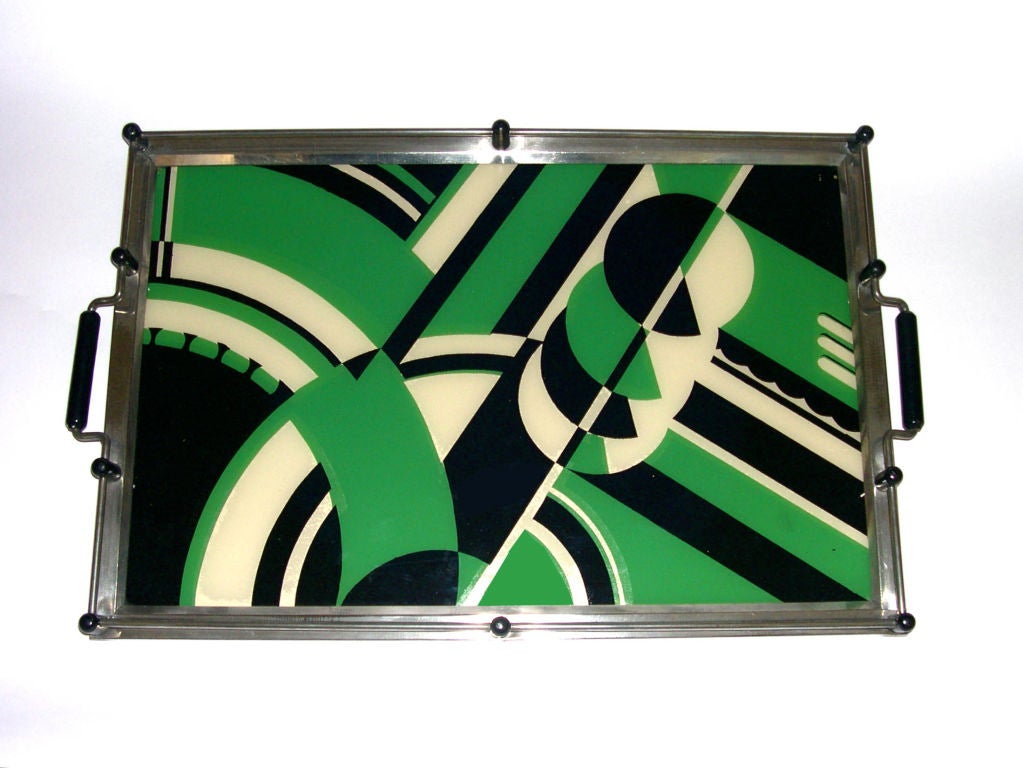 More commonly seen in red, this green version of the iconic Jazz Tray rarely surfaces. It is made of silk screened glass with metal and wood trim. It is a great expression of 1930's modern design.