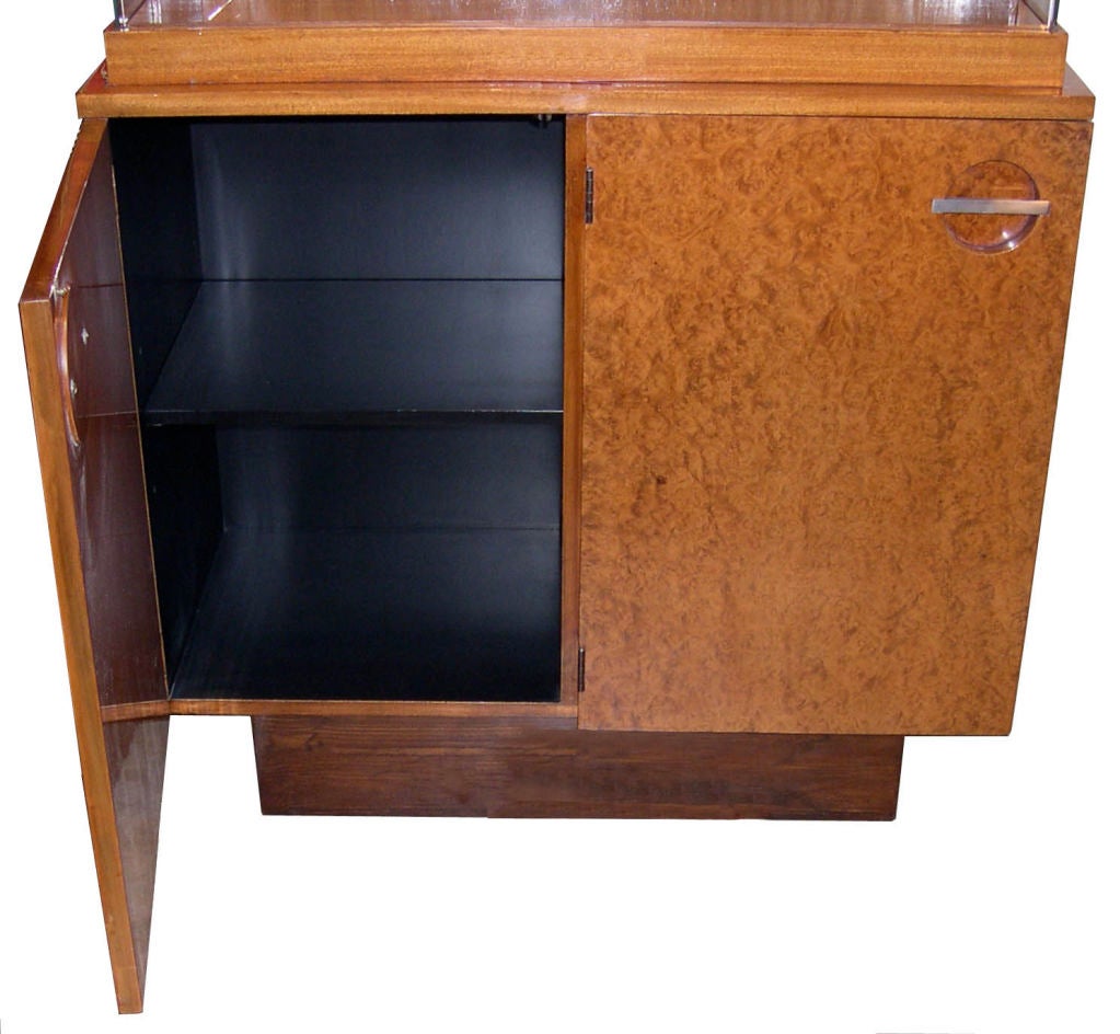 This beautiful cabinet was designed by Gilbert Rohde for Herman Miller in the 1930's.  The door fronts are maidou burl, the base is rosewood and the rest is mahogany.The display area  has sliding glass doors. It is finished in a beautiful hand