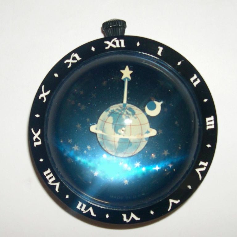 This whimsical, yet completely functional clock, was produced by Westclock in the early 1930's. It has a thick domed crystal which creates a feeling of looking into deep space when you look into the face. This is sealed with a bakelite ring that has