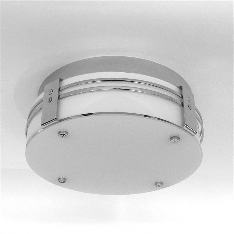 This rare ceiling mounted light has a white glass diffuser on the bottom and a bent white glass insert on the side. This is incased in a streamline banded chrome fitter. The flat glass is held in place by four screws on the bottom which can be