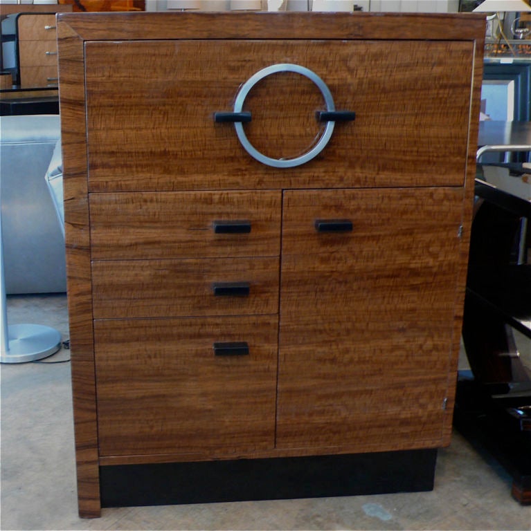 Part of the East Indial Laurel Wood series, this wonderful drop front secretary defines some of the best of Gilbert Rohde's design elements. From the machine age satin chrome circular handle to the beautifully planned veneer patterns and even the