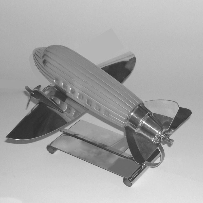 This wonderful airplane lamp was designed and produced in the 1930s. It holds a tubular light bulb inside the removable glass shade which illuminates the fuselage. The on and off switch is at the back almost concealed in the chrome tail wings.