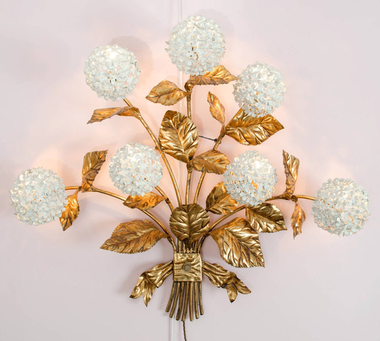 Rare American 1950s wall light in gilded brass with white enamel hydrangeas in the form of an ornate bouquet. An abundance of leaves with seven flowers in full bloom each giving a glamorous diffused light.
Matching standard lamp and wall light