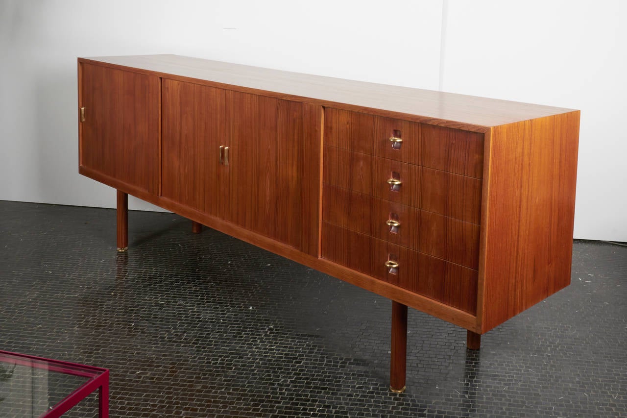 Extra-long teak sideboard marked NM, Neils Møller, Denmark, 1960s. Tambour doors in the middle, cabinet on the left, and drawers on the right with brass ring pulls.