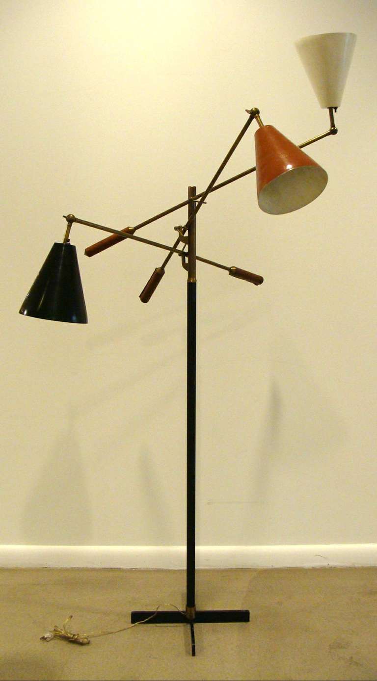 An original mid-century three-arm floor lamp featuring brass armature with leather-wrapped handles, , multi-color cones (black, brown, and white) and a rare cruciform base in black enameled steel.  Fine original patina.