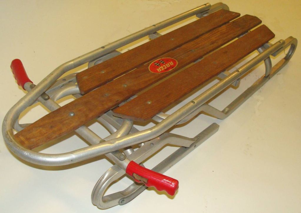 (NOTE:All aluminum sled shown on left is SOLD).<br />
Superb Aluminum sled crafted by Duralite of Passaic, New Jersey in the early 1950's.<br />
<br />
Aluminum with oak/wood slats. Spring-mounted front end for steering with original red grips. 