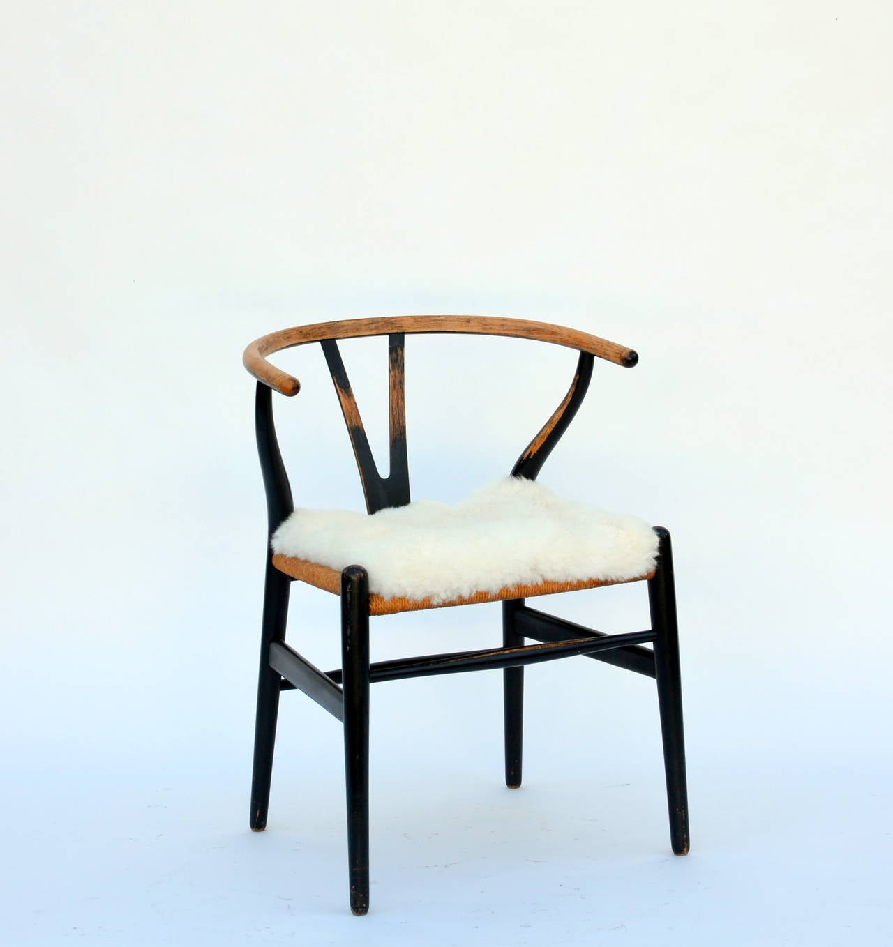 Ebonized teak and rope wishbone chair by Hans Wegner. Natural soft alpaca seat cover.