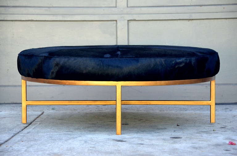 Chic oversized gilt metal and black calfskin ottoman. Firm seat. Also great as a round coffee table.