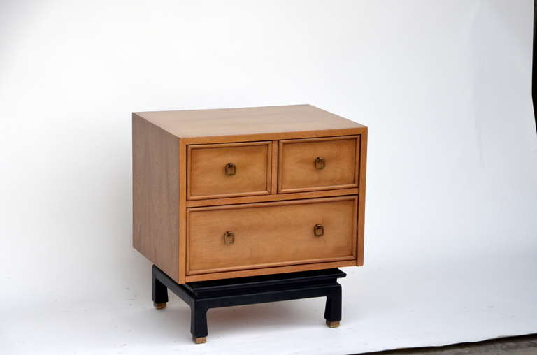 Pair of bleached mahogany night stand by American of Martinsville. Features drop ring brass pulls and black lacquered and recessed four leg platform base with brass sabots.