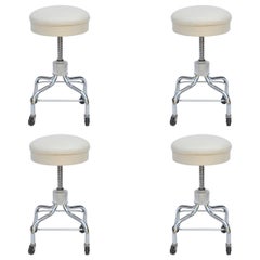 Juego de cuatro taburetes rodantes vintage cromados y de cuero blanco ajustables