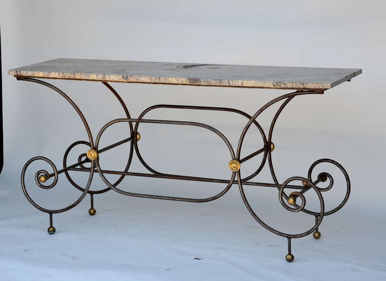 Elegant French iron baker's table with original marble top and gilt bronze finials. Very sculptural piece. Great as a console or a sofa table.