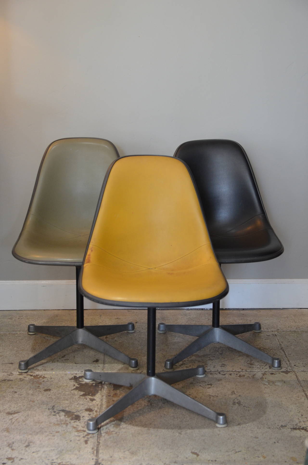 Ensemble de 3 chaises pivotantes vintage par Eames pour Herman Miller. Un noir, un gris et un jaune foncé.