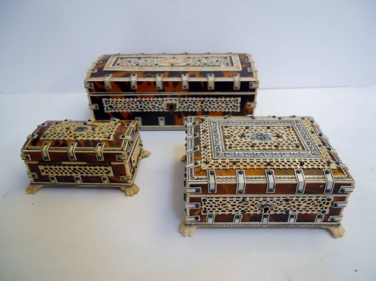 Three mid 20th century Anglo Indian boxes with strap design. Made of bone and shell. Please note that the smallest box is missing some fretwork on top of the box.

Largest measures 7w x 3d x 2.5h
Medium measures 5w x 4d x 2.25h
Small measures