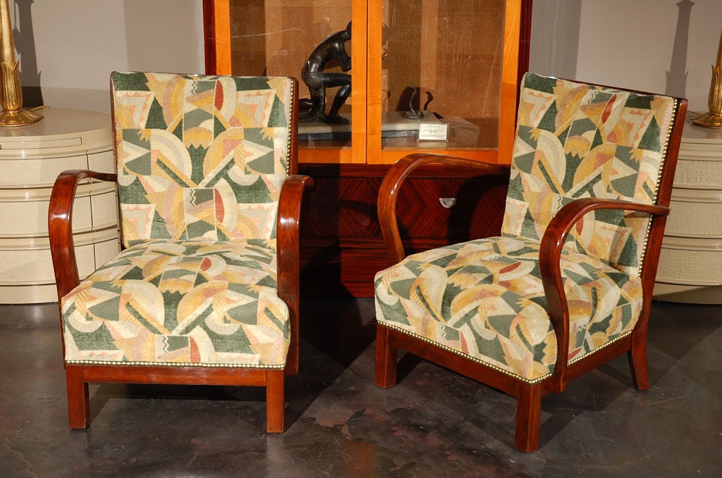 A smaller scale pair of stunning Art Deco armchairs. Chairs have been reupholstered in an Art Deco fabric designed by Robin Roberts, the founder of Clarence House. Brass nailead detail all along the edge of the upholstery. Note the unique curved