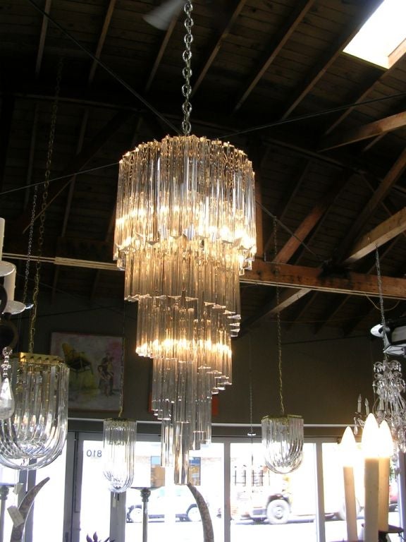 An elegant glass swirl chandelier with 5 interior lights and polished chrome hardware. Each glass rod measures 12 inches long.