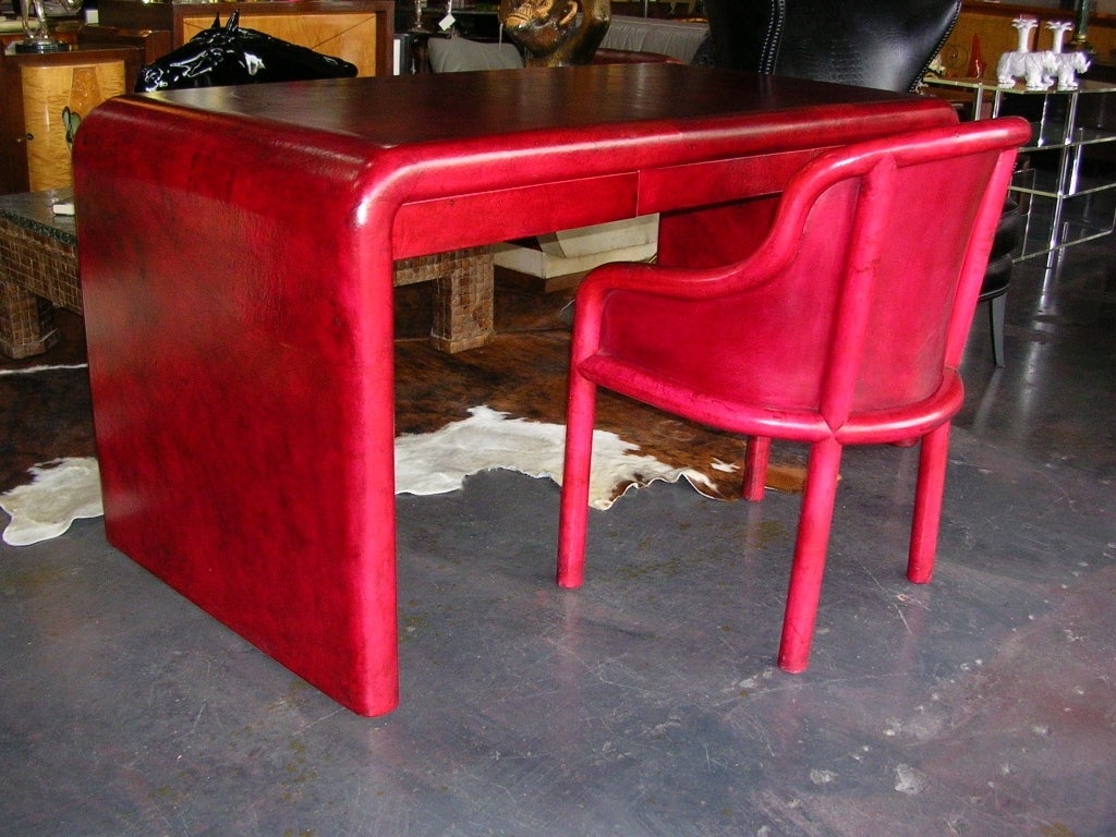 A red leather clad parson's style desk and chair by Karl Springer. Desk has three drawers. Chair is cushioned and very comfortable. Although color looks pinkish due to the flash, the actual color is more deep red like in Image 5.

Desk Size: 64