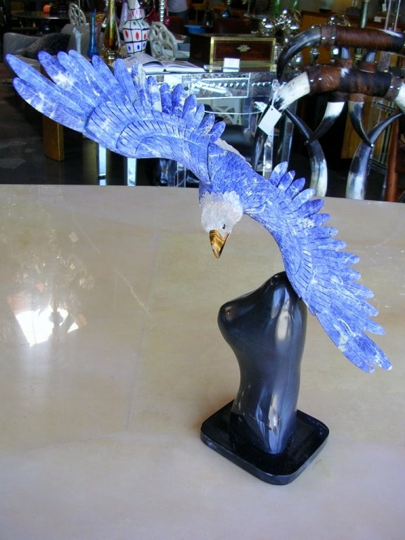 A remarkable eagle sculpture made of lapiz and rock crystal. Beak is tiger's eye. Claws are gilded bronze. All mounted on a black marble base.