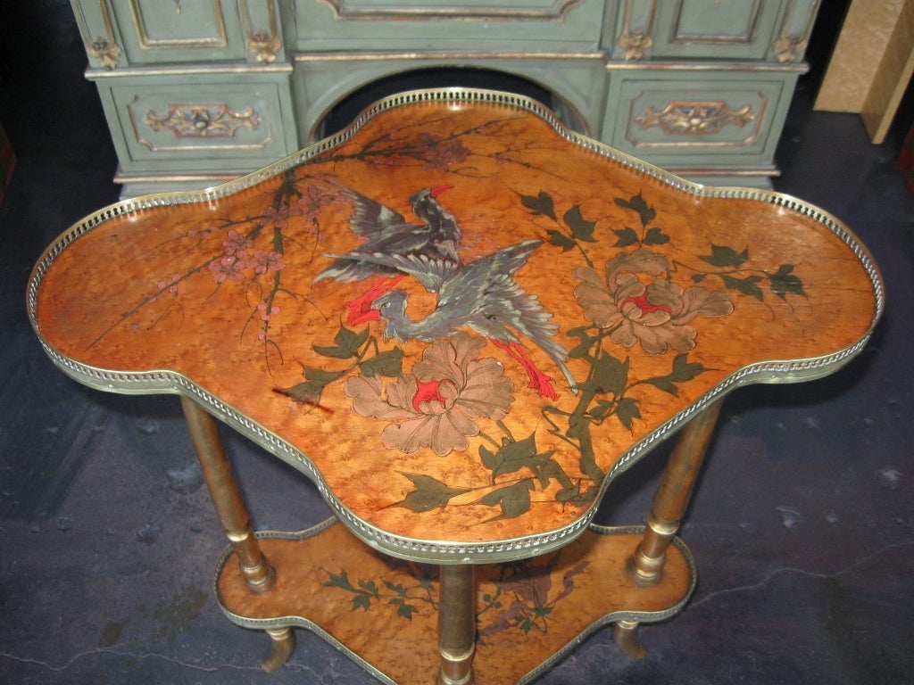 A unique hand painted Italian table with two levels and brass galleries and legs.  Top level is painted with birds, flowers and foilage. Bottom level is painted with leaves and flowers.