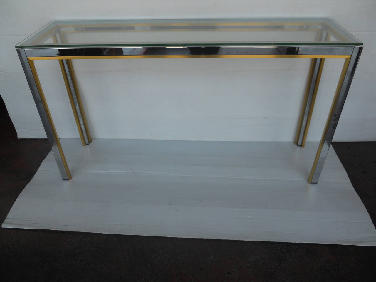 Sleek Italian console made of chrome with brass detail and clear glass top.