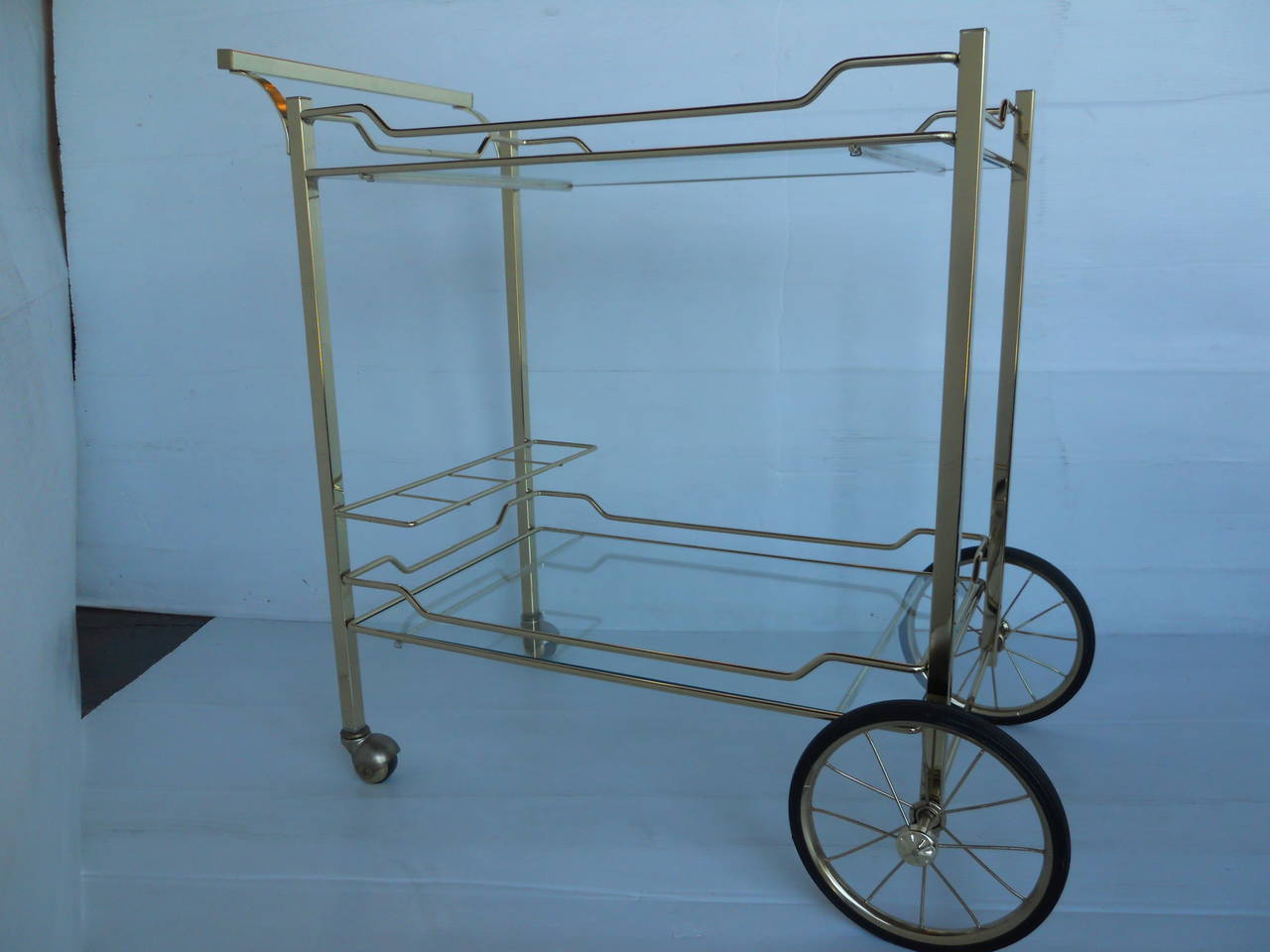 A Mid-Century brass bar cart. Has two levels and a brass gallery to hold bottles on the lower level.
