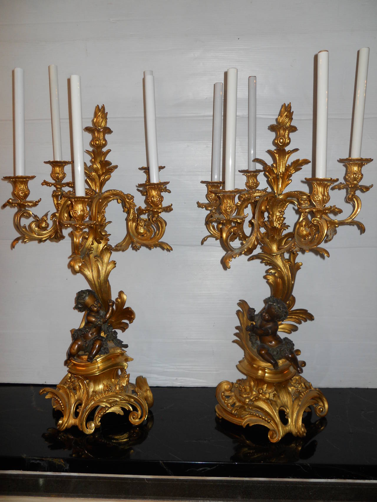 An impressive pair of French gilt and painted bronze six-light candelabras attributed to Victor Paillard.
The foliate scroll branches above a seated putto on pierced rocaille foliate and c-scroll base.