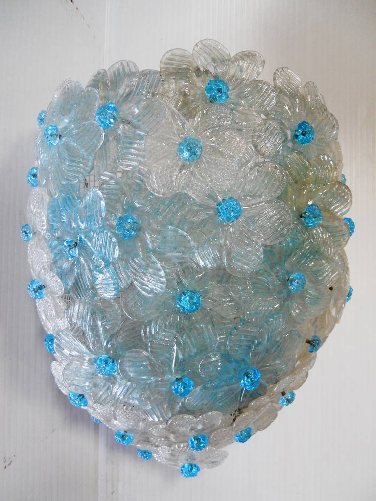 Single floral shield sconce. Consisting of clear petals with aquamarine centers. Interior has one candelbra socket.