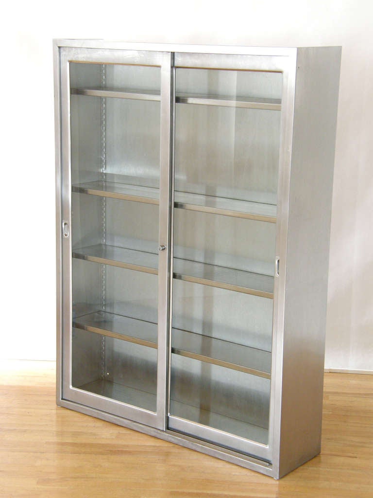 Industrial stainless steel cabinet with sliding glass doors and adjustable shelves. There is a 3/4
