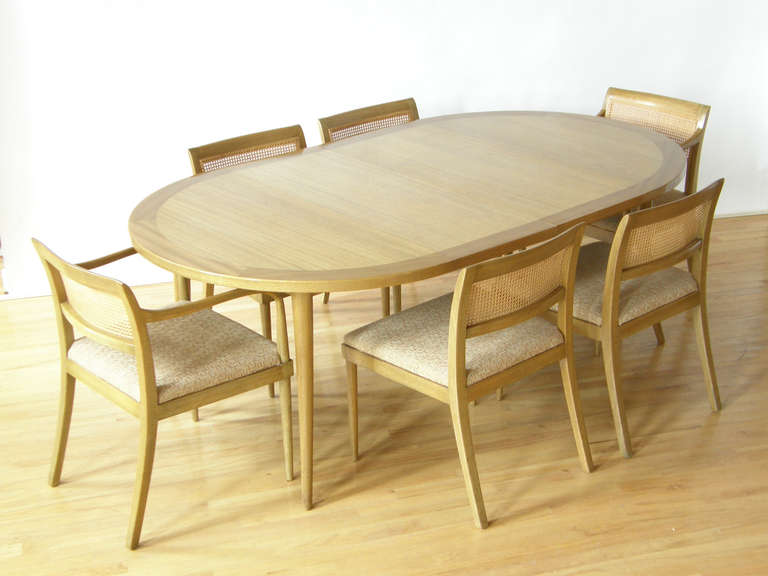 This light mahogany dining set was designed by Harvey Probber. The saber leg dining table has a two tone top with a darker band trimming the edge. It has six matching chairs, four armless and two with arms.

47.75