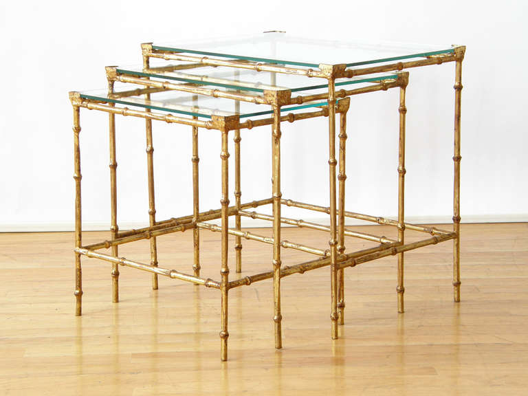 Set of three gilt iron, faux bamboo nesting tables with glass tops. Nesting tables are so versatile, as they can be tucked away or pulled out when more surfaces are needed. The measurements given are for the largest table.

Please contact us if you