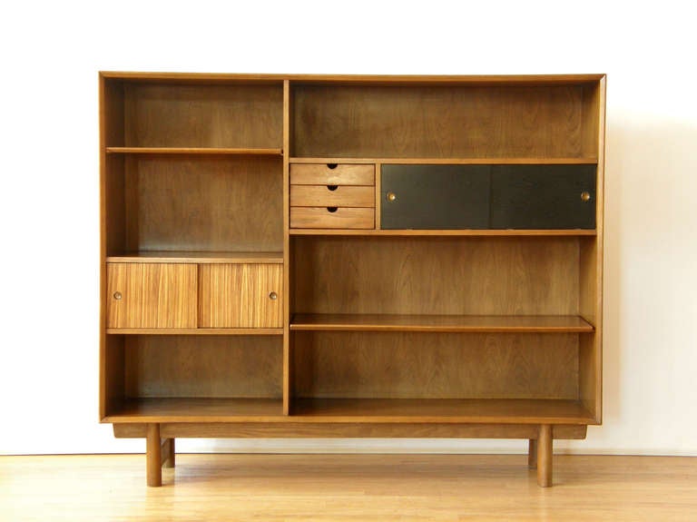 Bookcase / display cabinet designed by Lawrence Peabody for Richardson Bros. Co. This piece features two adjustable shelves, three small drawers and two sections with sliding glass doors. The asymmetrical design is accented by different wood veneers