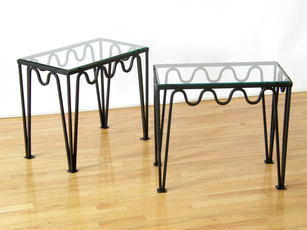 End tables with playful squiggling iron frames and glass tops. Frames are made from hollow stock. Glass sits on top of frames that have small tabs which hold them in place.