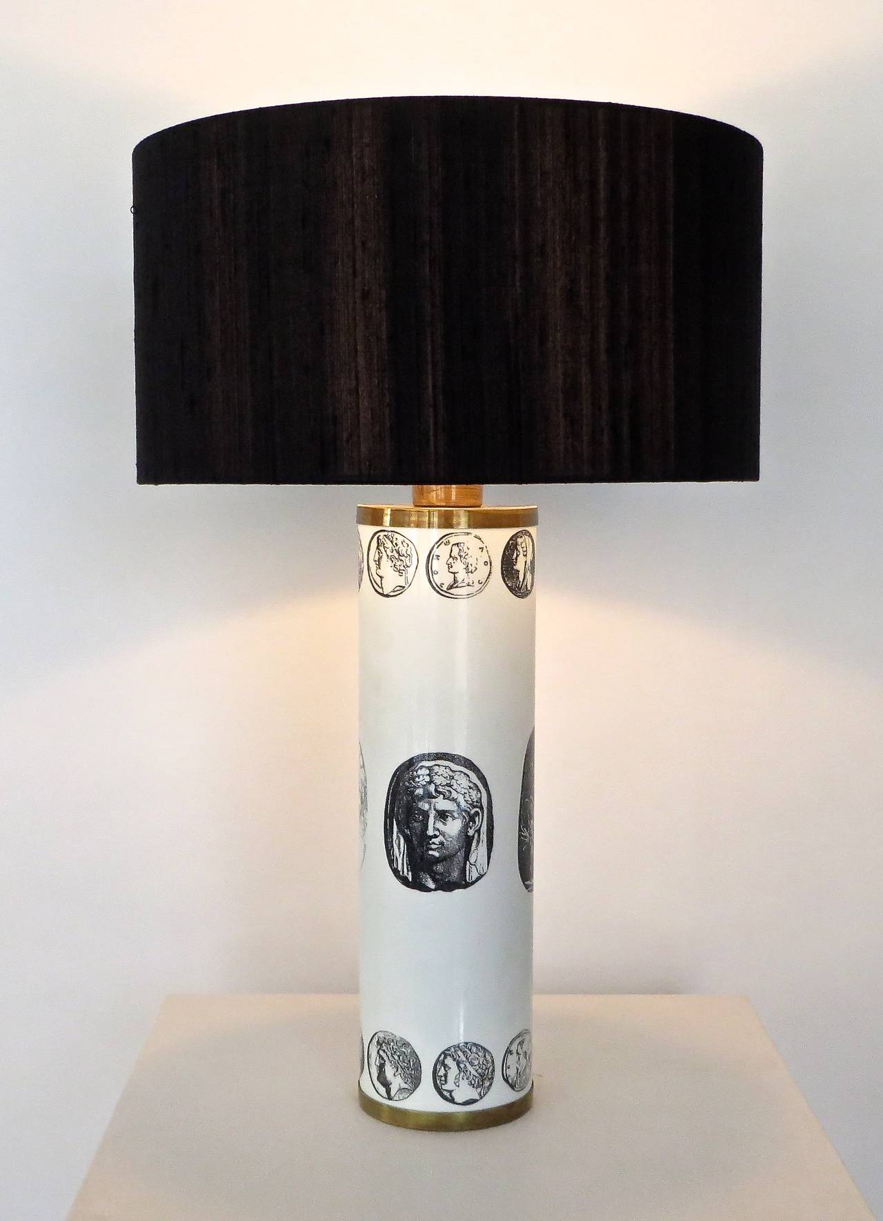 Piero Fornasetti enameled table lamp in white with black transfer printed lithographic cameos of emperors with brass details in beautiful condition. Signed with early label. 
Shown with black linen shade: 7.5