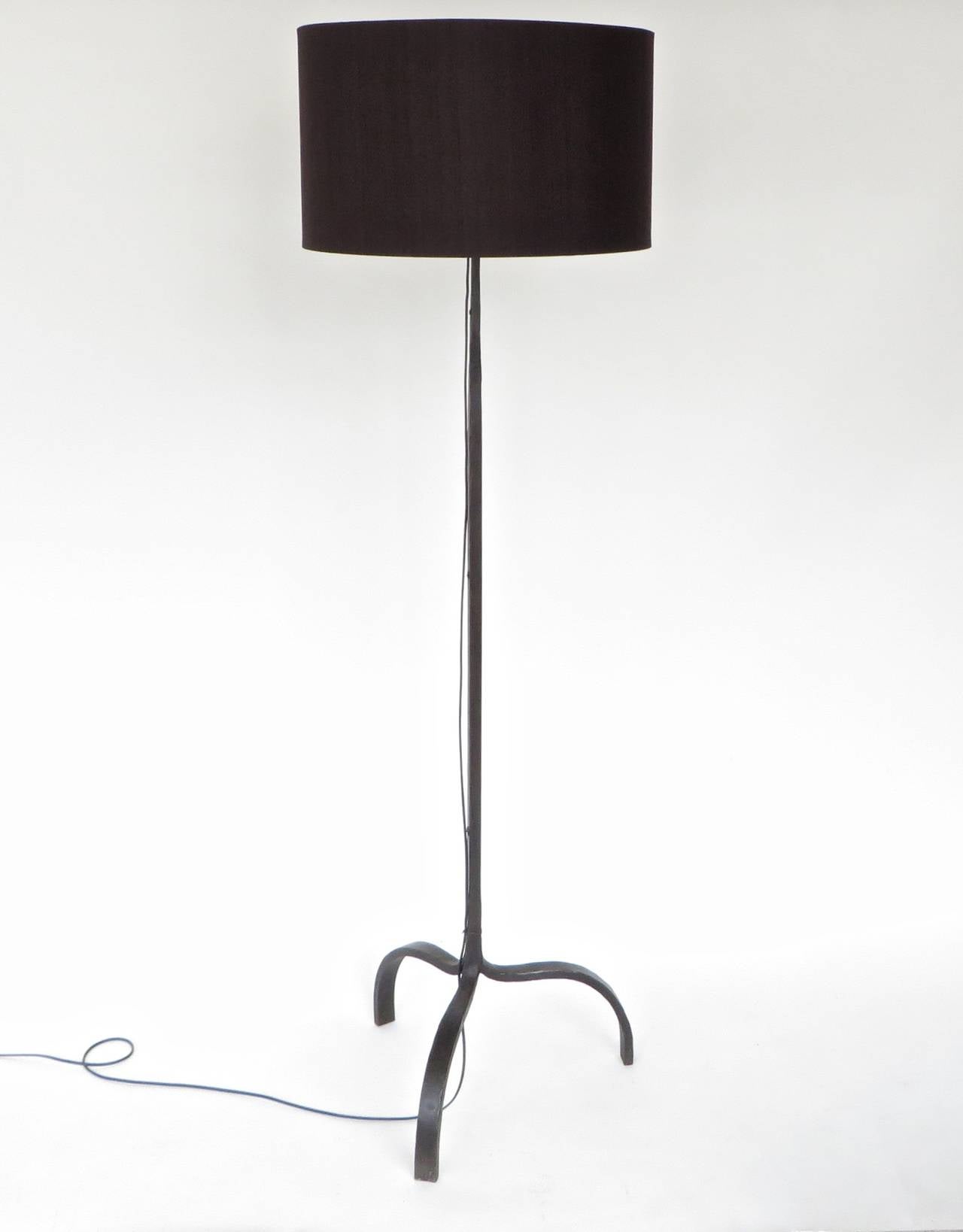 A very chic and minimalist aesthetic French hand wrought iron and patina black floor lamp on 3 splayed feet. Exceptional subtle detail to the iron in its making: see detail photos. The body of the lamp tapers from wide to slender as it ascends to
