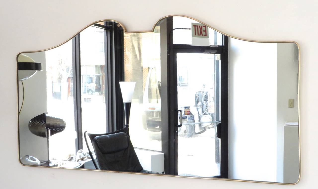 An Italian brass framed mirror with a double curved top. 
The mirror height at the top of the curve top is 28.75.
and the mirror height at the side edge or shoulder is 24 