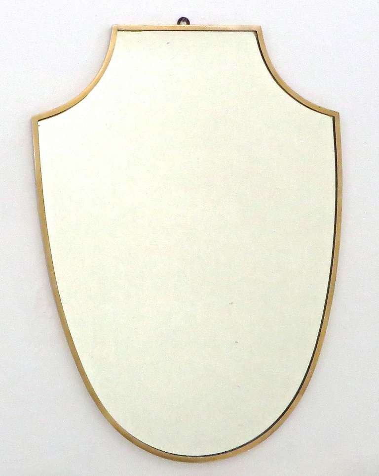 Brass framed Italian mirror, Italy, c. 1950. Brass shows beautiful, age appropriate patination. Shield shaped, with wood back. In the manner of Gio Ponti