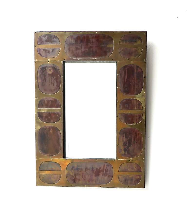 French hand cut and decorative nail head bradded mosaic mirror in patinaed two toned brass. The top layer is pierced and cut to reveal the darker patinaed bottom layer. Signed Blazy. Metal over black ebonized wood frame.