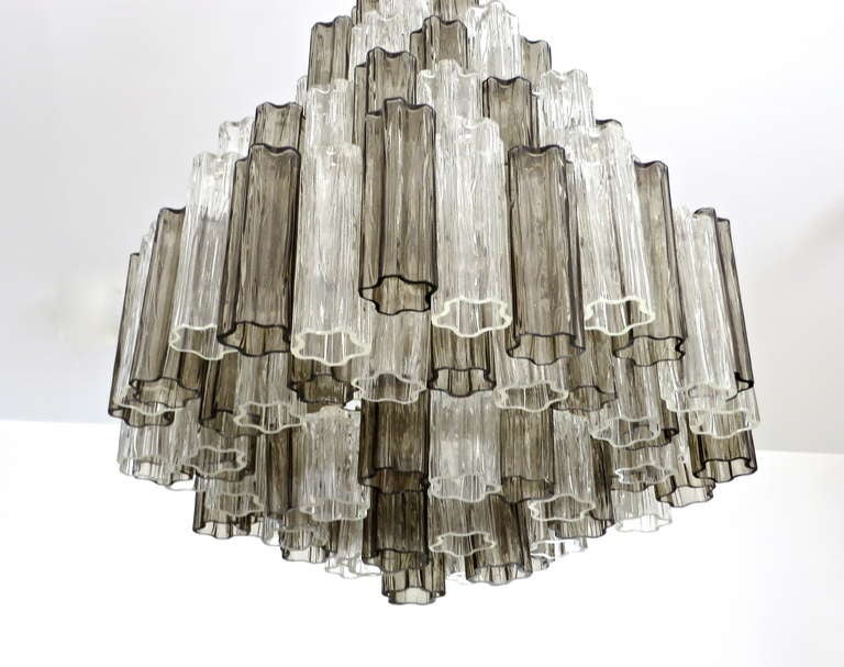 Murano molded Tronchi tube glass Chandelier by Camer, Italy.
C 1970. 114 clear and smoke grey pieces of hand blown glass, on a chromed structure. Seven tiers of glass, 12 light sources. Glass can be arranged differently according to size of glass