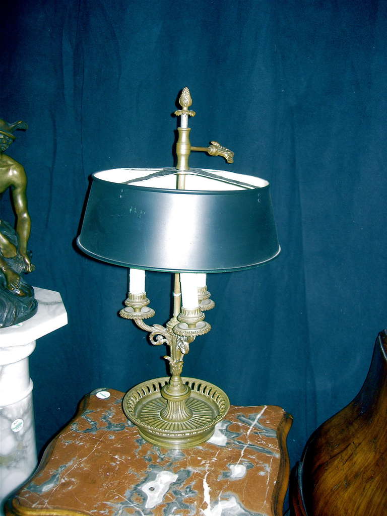 A Louis XVI Style Bronze Bouillotte Lamp, 
having a shaped standard issuing three foliate scroll and cornucopia cast candle arms raised on a pierced circular base, surmounted by a tole shade.