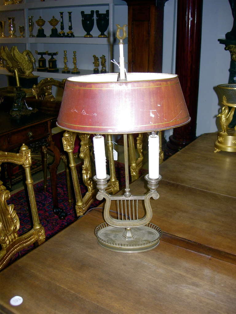 A Directoire Gilt Bronze Bouillotte Lamp, 
the standard of lyre form issuing the twin candle arms, raised on a circular galleried base, set with a tole shade.