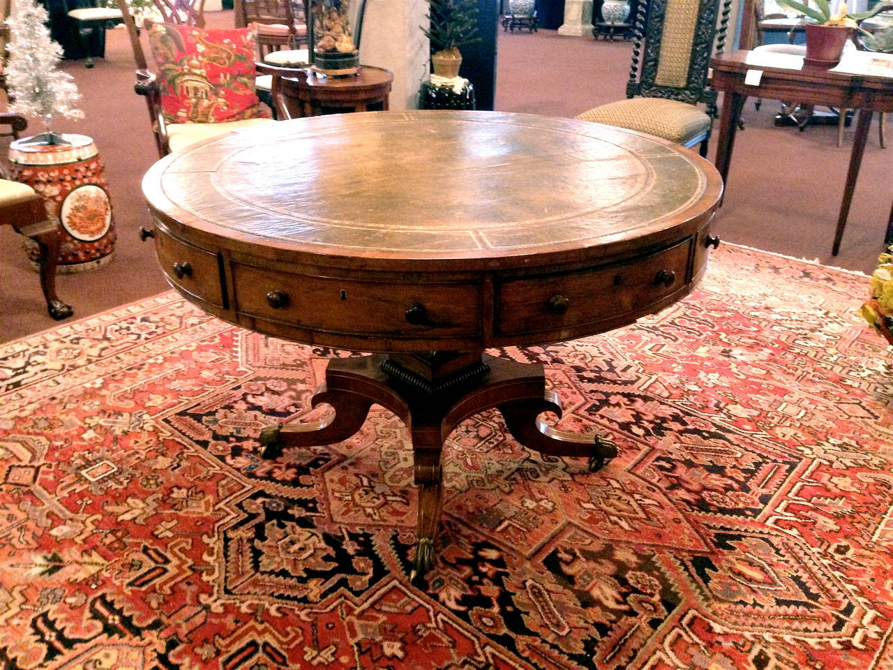 Exceptional English Regency rent table. Bearing drawers beneath. With a leather top bearing gilt embellishments. With brass paw feet. Raised on casters. Swivel top.