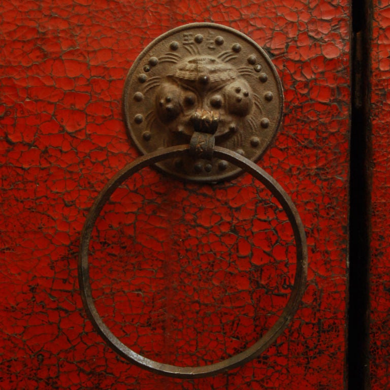 A pair of monumental 19th century Chinese courtyard doors with heavy red crackle lacquer finish and large iron hardware.