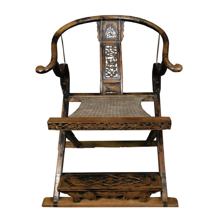 A wonderful pair of folding chairs from China. These chairs feature a woven seat and wood frame. The carved backsplat depicts a Qilin amongst vines.