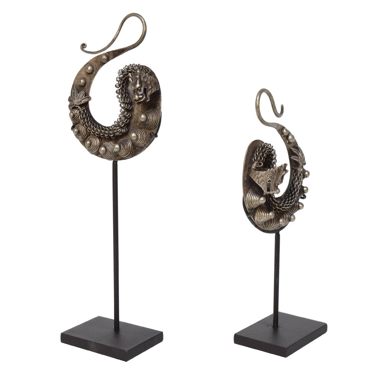 A pair of silver dragon earrings from Guizhou Province, China on custom made stands. These c. 1900 pieces were crafted by the Miao people, one of the official minority groups in China.