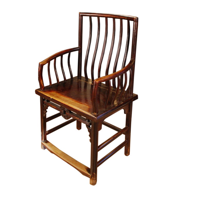 Carved coins, which represented prosperity, appear to be held in place by stretchers carved to look like ropes beneath the seat of these 19th century Chinese elmwood spindleback chairs. The chairs have unusually bowed spindle arms. The original