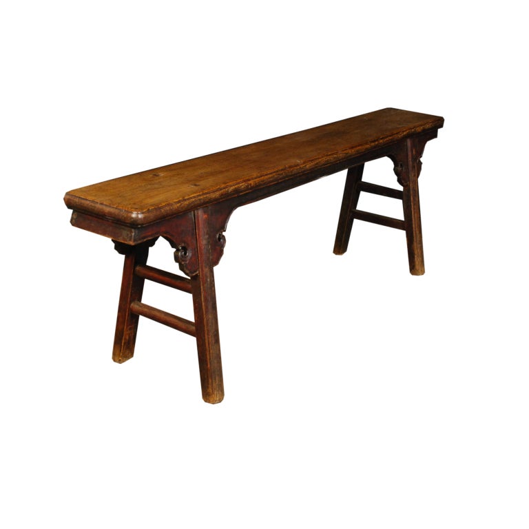 A 19th century provincial Chinese elmwood bench with tapered legs and cloud carved spandrels.
