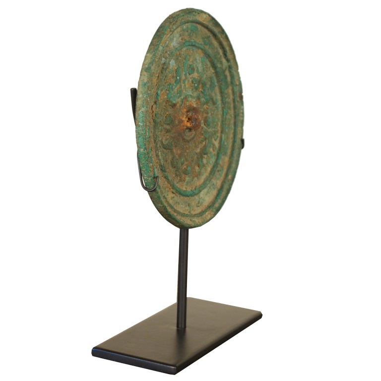 A Han period Chinese bronze mirror with running dog relief pattern, and wonderful patinated finish, mounted on custom stand.